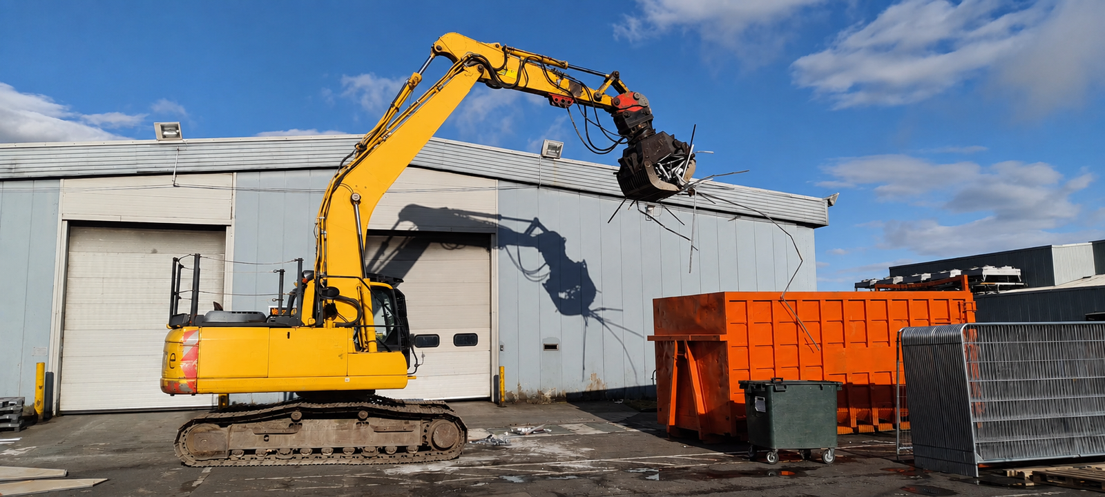 Excavator with demolition grapple removing roof cladding during mechanical demolition